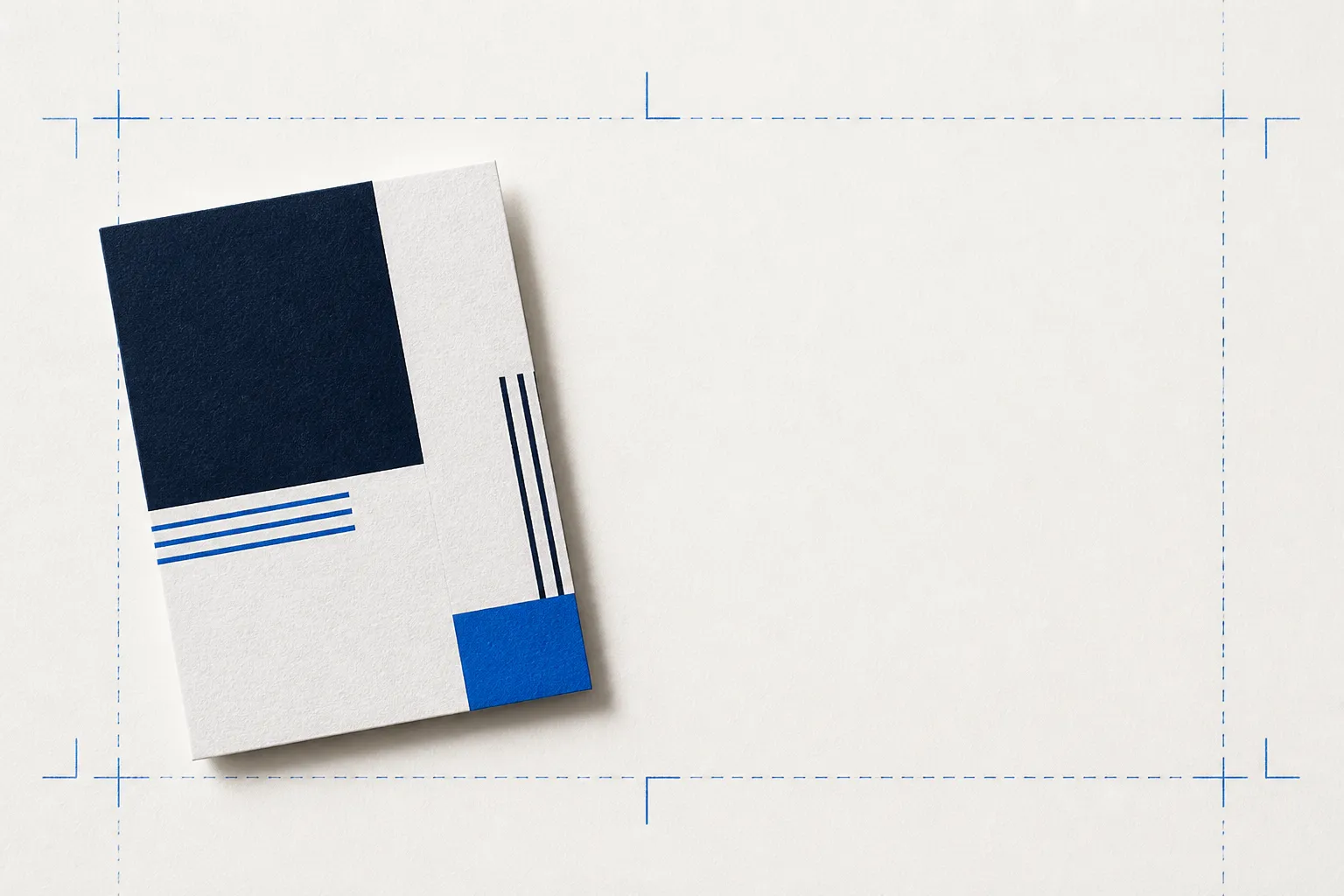 A printed card on warm paper framed by blueprint-blue registration crop marks and dashed bleed guide lines, showing where the trim is cut and how artwork extends into the bleed.